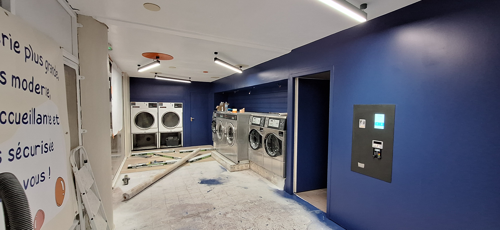 Laverie rénovée avec peinture bleue et machines installées