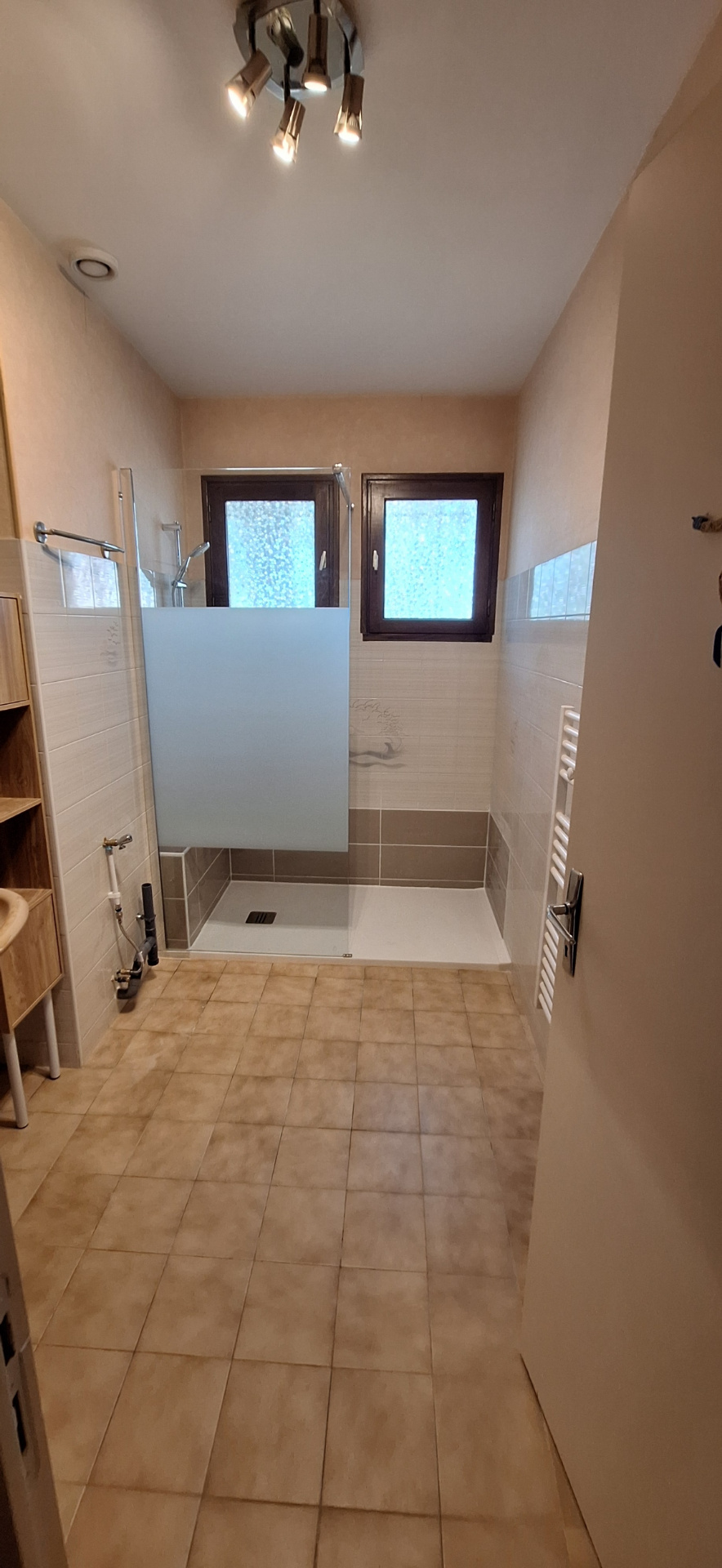 Salle d'eau rénovée avec douche, paroi en verre et carrelage